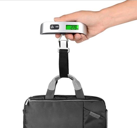Hand die een zilverkleurige digitale bagageweegschaal met groen display (2.15 kg) boven een grijze tas vasthoudt.