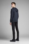 Model draagt een donkerblauwe hoodie met rits en een zwarte jeans.