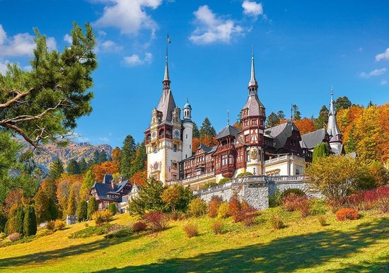 Kasteel Peles, Roemenië, omgeven door herfstbomen en glooiende grasvelden.