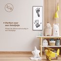 Een lijst met een hand- en voetafdruk, naast een kinderkamerinrichting.