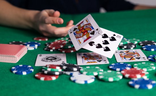 Kaarten met 10 schoppen en Boer schoppen vallen op groen kleed tussen pokeren fiches.