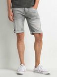 Gedeeltelijke weergave van een man die een grijze denim short draagt met opgerolde zomen. Hij draagt witte sneakers.