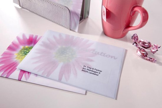 Enveloppes transparentes à motif floral, adresse écrite dessus, à côté d'une tasse de thé