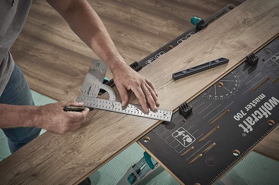 Man die met een winkelhaak en liniaal op een laminaatvloer werkt. Wolfcraft Master 700.