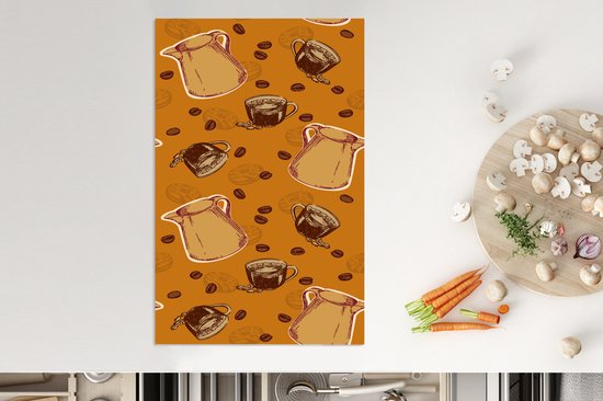 Oranje kookplaatbeschermer met een patroon van koffiekannen en -kopjes, nabij groenten.