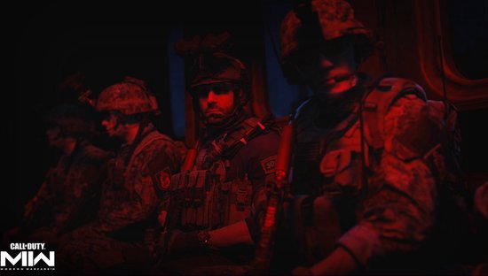 Vier soldaten met uitrusting in een donkere ruimte verlicht met rood licht.