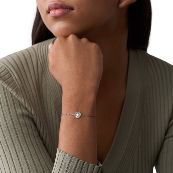 Model draagt een zilverkleurige FOSSIL armband met een ronde, glinsterende hanger.