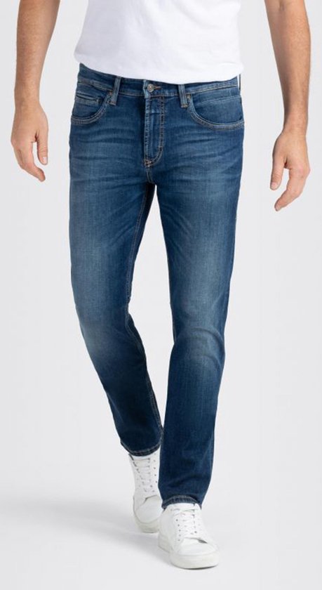 Man met een blauwe jeans, wit T-shirt en witte sneakers.