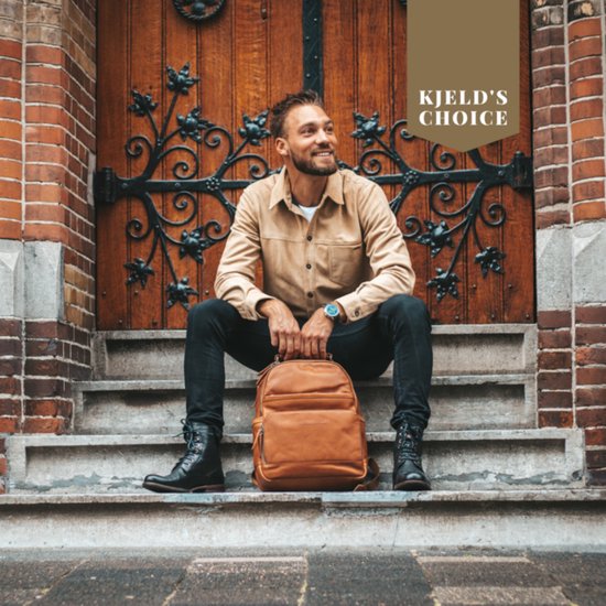 Man zittend op trappen met cognac leren rugzak, bij houten deur.