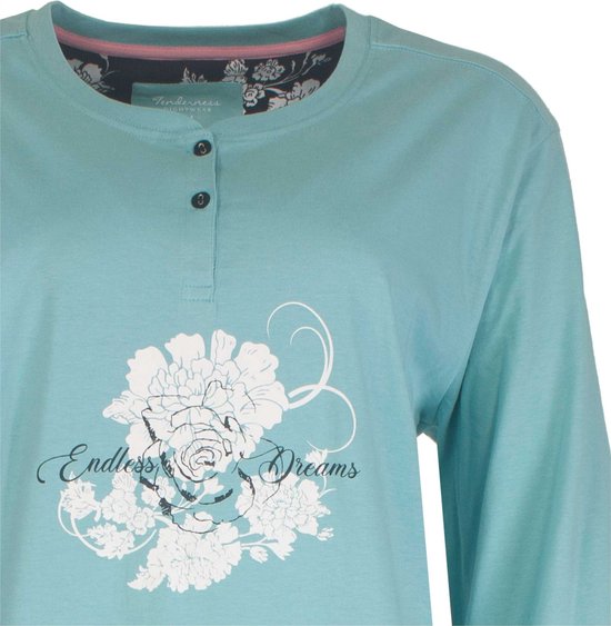 Close-up van een lichtblauw pyjamashirt met knoopjes en een witte bloemenprint met de tekst 'Endless Dreams'.