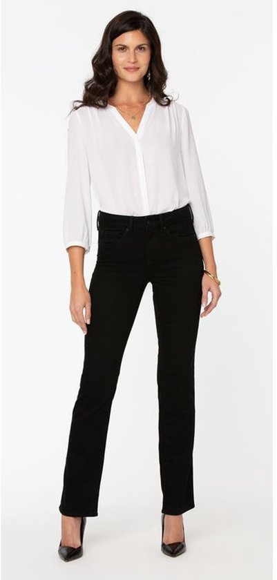 Model in zwarte jeans met rechte pijpen en hoge taille. Ze draagt een witte blouse.