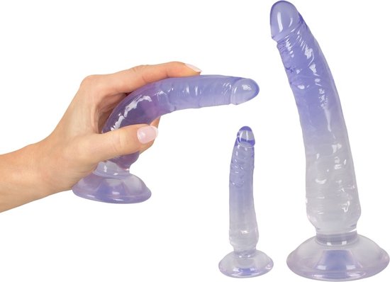 Een hand houdt een transparante paarse dildo vast. Twee andere dildo's met zuignappen, van groot naar klein.