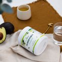 Pot met 'Collageen Premium' en bosbessensmaak, naast een avocado, glas water en kop thee op een bruine doek.