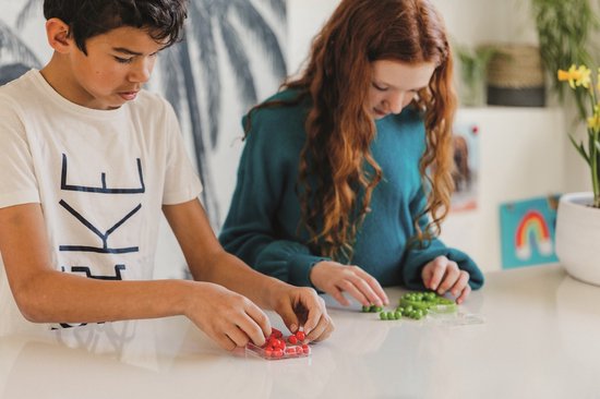 Jongen en meisje met rood en groen speelgoed op een tafel.
