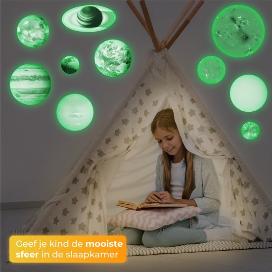 Une fille lit dans une tente tipi, entourée d'autocollants de planètes vertes phosphorescentes sur le mur.