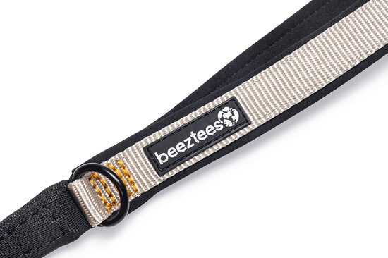 Zwarte handgreep met beige band en Beeztees logo. Bevestigingsring aan de onderkant.