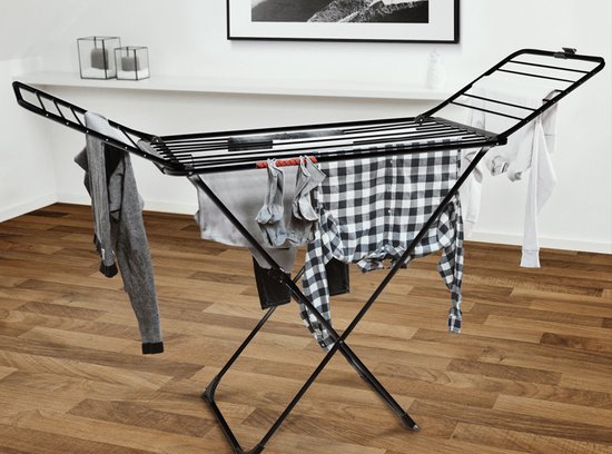 Étendage noir déplié avec vêtements et chaussettes, avec accessoire Vileda, sur plancher en bois.
