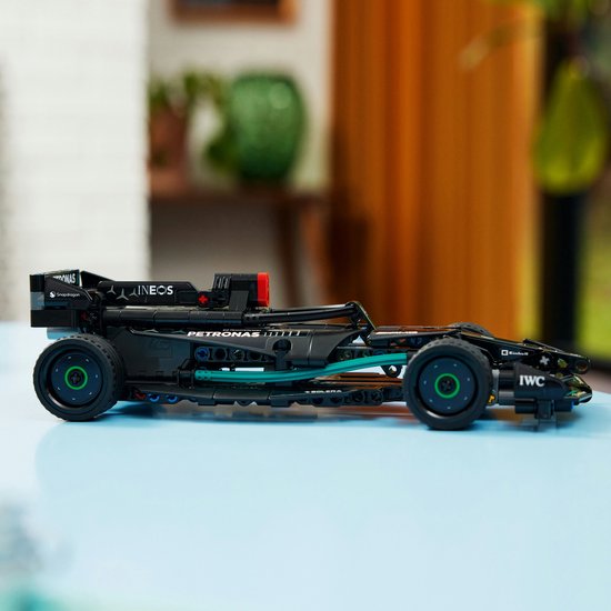 Zwarte LEGO Formule 1 auto op een blauwe tafel, zijaanzicht met PETRONAS en IWC logo's.