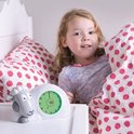 Sam Slaaptrainer naast een slapend meisje in bed met roze gestippelde kussens.