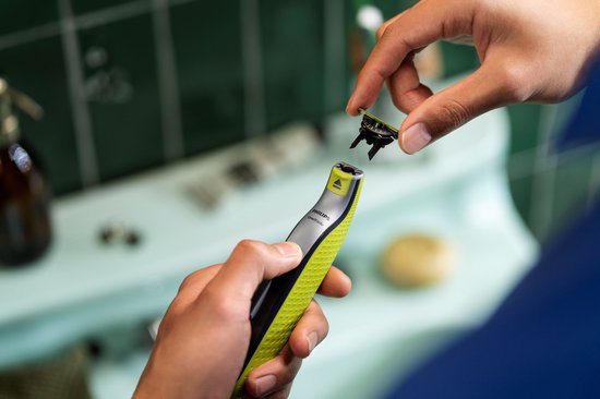 Hand met Philips OneBlade scheerapparaat, terwijl een ander hand een 360 mesje erop klikt.