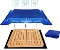 Een blauw afdekzeil ligt over een houten zandbak heen. Eronder ligt een gesloten zandbak en de losse zeil.