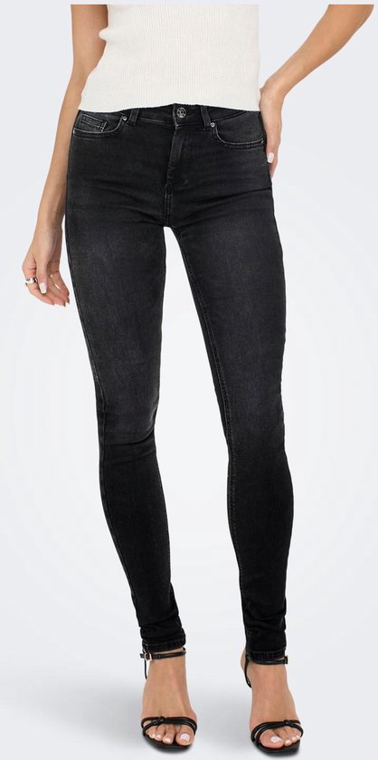 Model in skinny jeans in een donkergrijze wassing met hoge taille en enkellaarsjes.