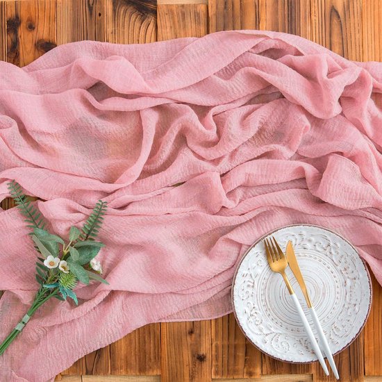 Chemin de table plissé en mousseline rose avec une assiette décorative et des couverts dorés.