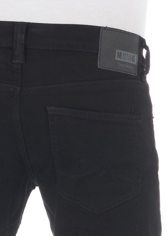 Close-up van de achterkant van een zwarte Mustang jeans. De broek heeft een leren Mustang logo met 'True Denim' erop.