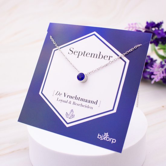 Zilverkleurige ketting met blauwe zirkonia hanger, op een kaart met 'September' en 'De Vruchtmaand'.