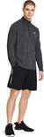 Man in zwart sportshirt met halve rits en zwart sportbroekje met logo op linkerbeen.