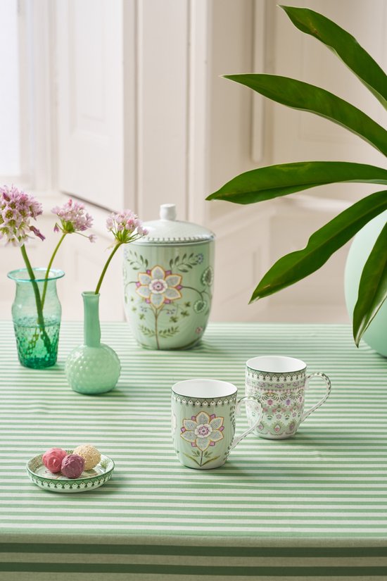 Twee lichtgroene Pip Studio mokjes met bloemenprint op een groen gestreepte tafel.