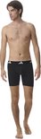 Man in zwarte Adidas boxer briefs met witte Adidas logo's op de tailleband.