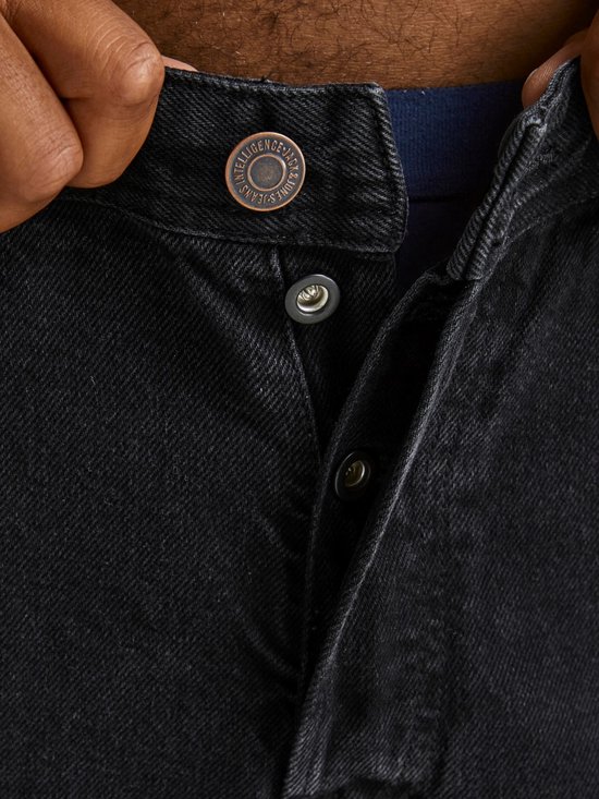 Sluiting van zwarte jeans met knopen.