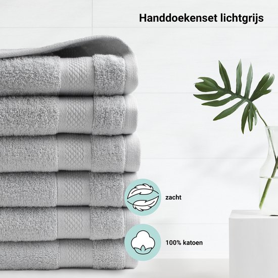 Stapel lichtgrijze handdoeken met een textuur van 100% katoen en een zacht gevoel.