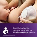 Un bébé tète le sein, à côté d'une coupelle Philips Avent remplie de lait.