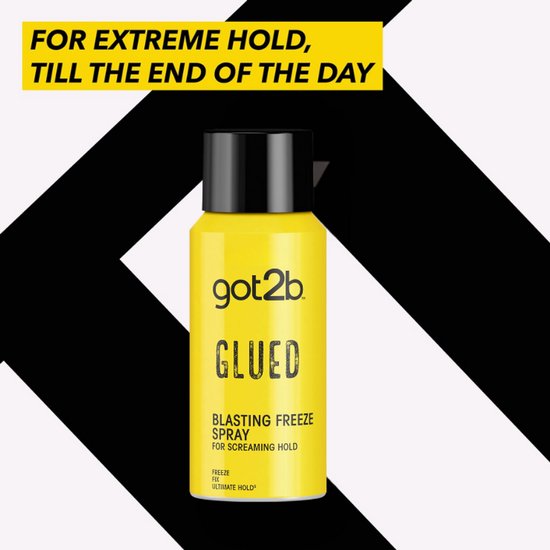 Gele Got2b Glued Blasting Freeze Spray met zwarte dop op een zwart-wit gestreepte achtergrond.