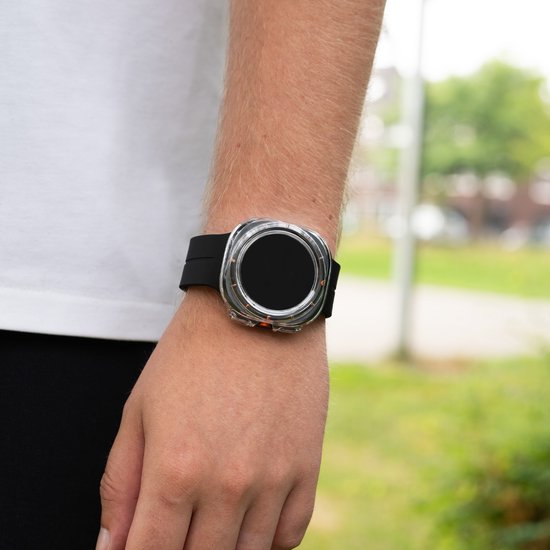 Zwarte siliconen band met een zilverkleurige smartwatch met een ronde wijzerplaat en oranje accenten, gedragen aan een arm.