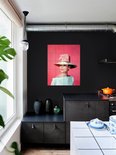 Audrey Hepburn portant un grand chapeau de paille avec un nœud rose, une robe bleu pâle épaules dénudées, sur fond rose, dans une cuisine.