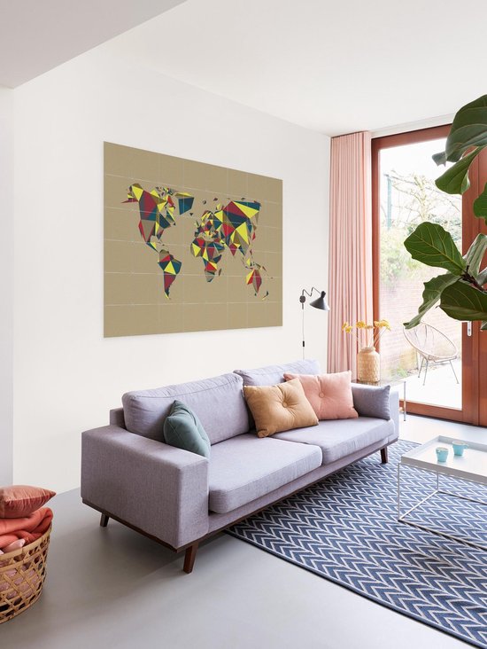 Carte du monde avec des motifs géométriques rouge, jaune et bleu, accrochée au mur au-dessus d'un canapé.