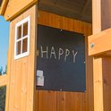 Chalkboard met het woord "HAPPY" geschreven met krijtjes, in een houten speelhuisje.
