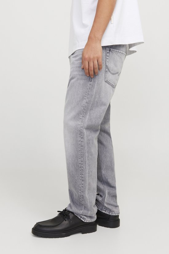 Zijaanzicht van een man in witte T-shirt en grijze jeans.