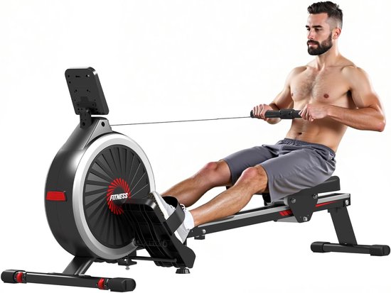 Een man met een baard en grijze short traint op een zwarte roeimachine met een groot rond vliegwiel, tijdens een full-body workout.