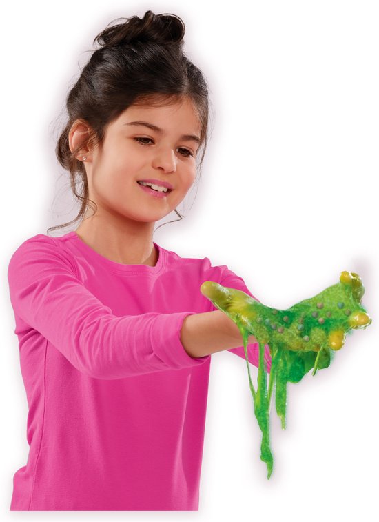 Meisje met knalroze shirt speelt met groen, glibberig slijm in haar handen.