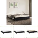 Zwart boxspringbed met witte matras, gestoffeerde basis en vierkante poten, in slaapkamer met planten en dekens.