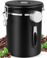 Zwart koffieblik van roestvrij staal met een zilverkleurige lepel en handvat, omringd door koffiebonen en groene bladeren.