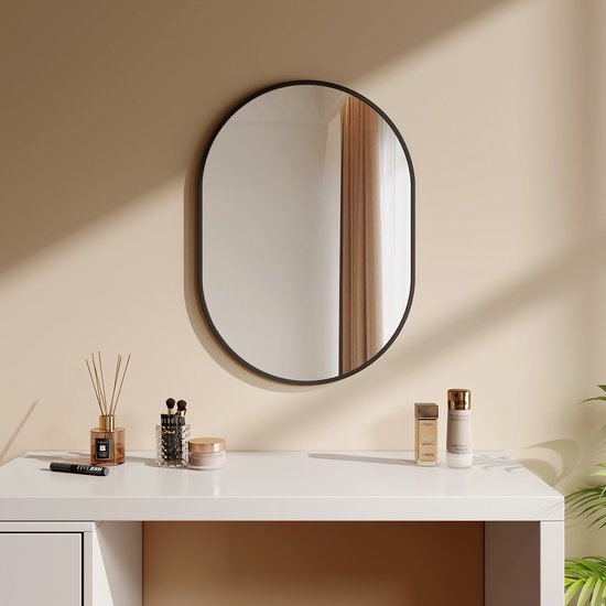 Miroir ovale à cadre noir au-dessus d'une coiffeuse blanche avec des cosmétiques.