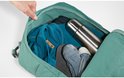 Donkergroene rugzak geopend met kleding, thermosfles en sokken erin.