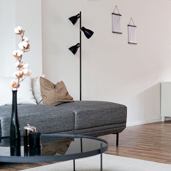Zwarte staande lamp met drie spots in een modern ingerichte woonkamer.
