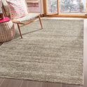 Un tapis beige à poils courts avec un motif chiné, dans un salon avec une chaise en bois et des paniers.
