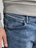 Close-up van de voorkant van een lichtblauwe jeans, met de rechterzak zichtbaar.